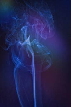 A vertical shot of smoke in colorfull backlight with a blue note