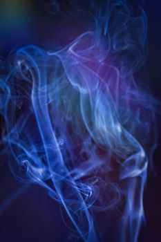 A vertical shot of smoke in colorfull backlight with a blue note