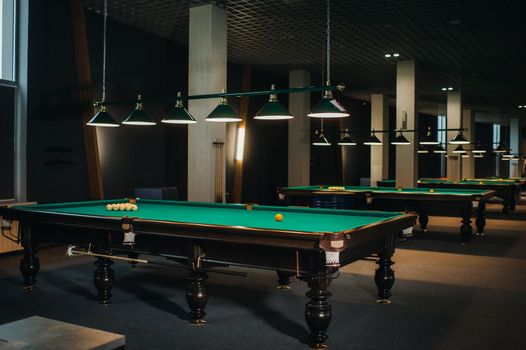 there are a lot of billiard tables with green surfaces and balls in the billiard club.