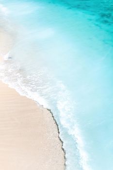 Tropical beach with a bird's eye view of the waves breaking on the tropical Golden sandy beach. Sea waves gently loop along the beautiful sandy beach