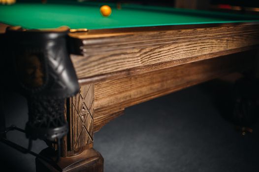 The oak decorative leg of a billiard table looks expensive.