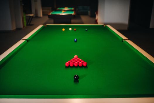 placing snooker balls on a green billiard table.