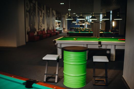 table and two chairs near the green-covered billiard table with balls in the billiard club.