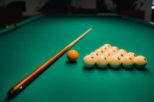 Playing pool on a green table.Balls and cue are laid out on the table.
