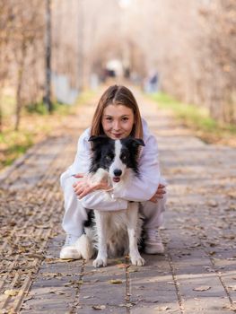 Caucasian woman hugging border collie in autumn park. Portrait of a girl with a dog