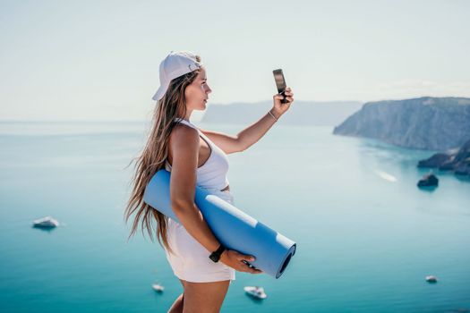 Young woman with black hair, fitness instructor in pink sports leggings and tops, doing pilates on yoga mat with magic pilates ring by the sea on the beach. Female fitness daily yoga concept