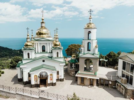 Christian church on a background of mountains. Temple of the Holy Archangel Michael in Oreanda. The southern coast of Crimea. Located on a rocky cliff and is surrounded by beautiful vegetation
