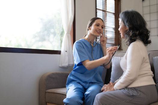 Asian nurse showing health checkup report to grandmather and giving advice. medical assisted living visit senior patient at home. Home nursing and healthcare caregiver concept..