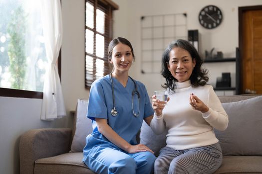 Asian nurse showing health checkup report to grandmather and giving advice. medical assisted living visit senior patient at home. Home nursing and healthcare caregiver concept..