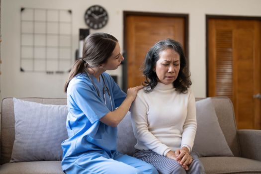 Young female physician leaning forward to elderly lady patient holding her hand in palms. supporting encouraging old person...