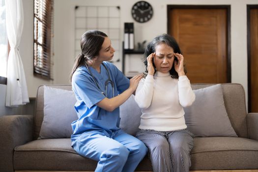 Young female physician leaning forward to elderly lady patient holding her hand in palms. supporting encouraging old person...