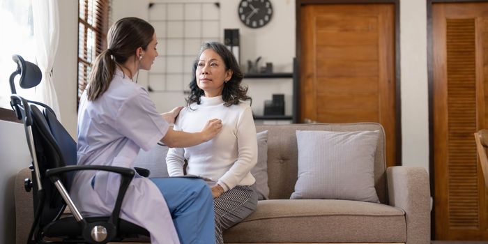 Asian female patient undergoing health check up while female doctor uses stethoscope to check heart rate in nurse, health care concept..