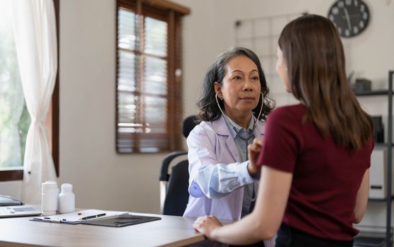 Serious doctor visiting female patient, giving consultation, recommendations, listening to complaints. woman complaining on healthcare problems to physician in white coat..