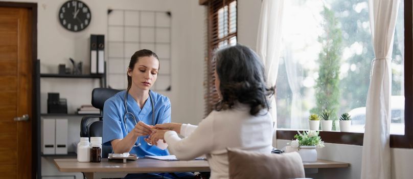 Asian Female Doctor examining and taking note on checklist paper with female patients in medical room...