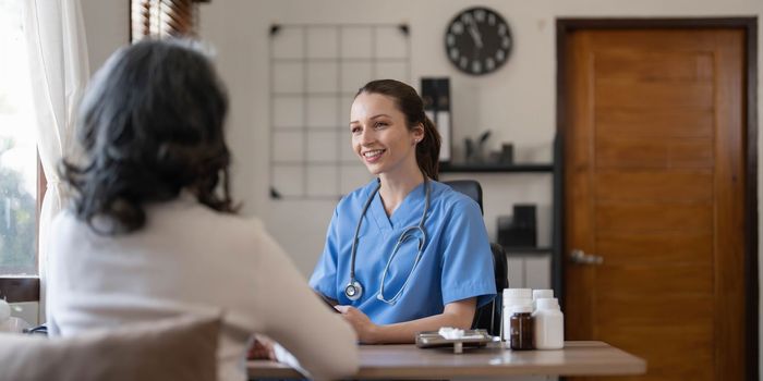 Asian Female Doctor examining and taking note on checklist paper with female patients in medical room...