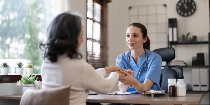 Asian Female Doctor examining and taking note on checklist paper with female patients in medical room...