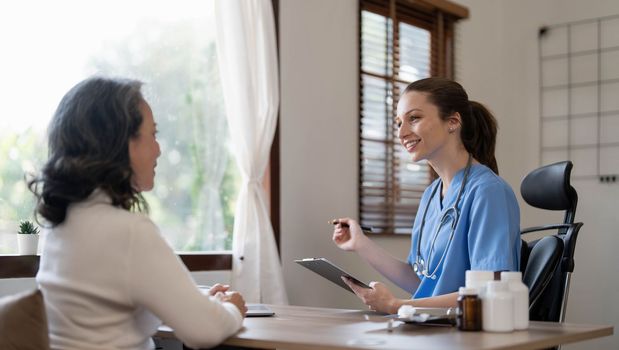 Asian Female Doctor examining and taking note on checklist paper with female patients in medical room...