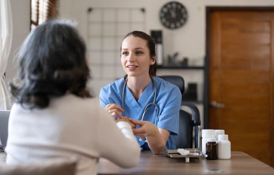 Asian Female Doctor examining and taking note on checklist paper with female patients in medical room...