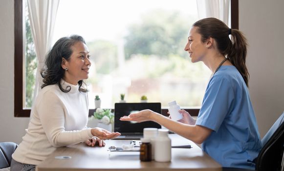 Asian Female Doctor examining and taking note on checklist paper with female patients in medical room...