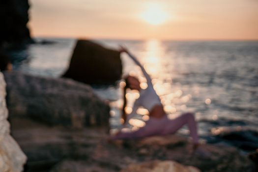 Young woman with black hair, fitness instructor in pink sports leggings and tops, doing pilates on yoga mat with magic pilates ring by the sea on the beach. Female fitness daily yoga concept