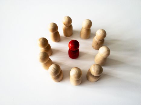Red wooden doll figure surrounded by other doll figure. Harassment concept.