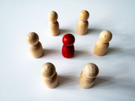Top side view of red wooden doll figure surrounded by other doll figure. Harassment concept.