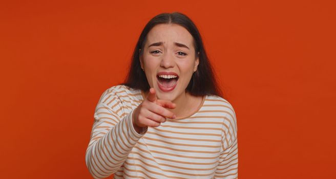 Amused pretty woman pointing finger to camera, laughing out loud, taunting making fun of ridiculous appearance, funny joke anecdote, bullying. Young adult girl isolated alone on red studio background