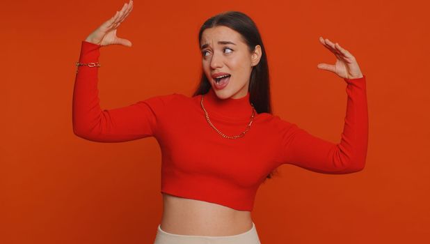 Bored pretty young woman in crop top showing blah blah gesture with hands, has not interested in the conversation, gossips, empty promises, lier. Millennial girl isolated on red studio background