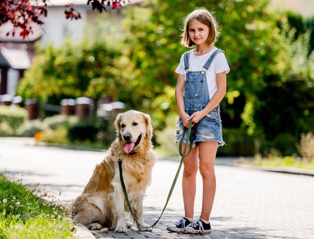 Preteen girl with golden retriever dog walking in beautiful park at summer. Cute child kid with doggy pet together outdoors