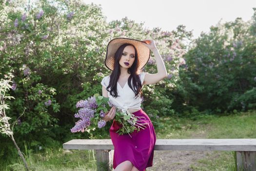 A fashionable girl with dark hair, a spring portrait in lilac tones in summer. Bright professional makeup