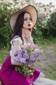 A fashionable girl with dark hair, a spring portrait in lilac tones in summer. Bright professional makeup