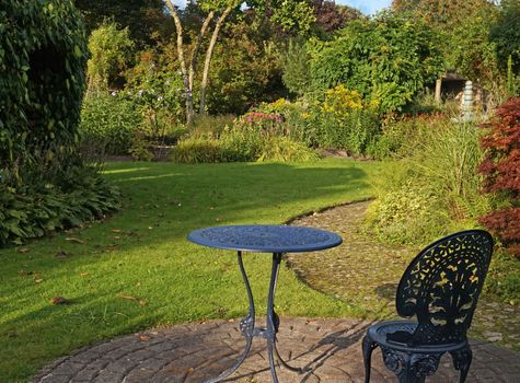 Romantic garden in summer with blue chair and a round table