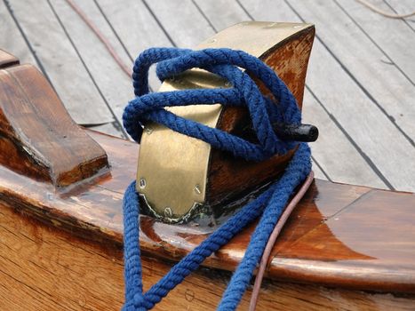 Mooring bollard on the deck of a wooden ship with a blue rope. It's a historical Dutch fishing boat in Elburg, the Netherlands