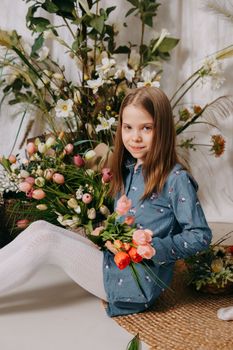 Two girls in a beautiful Easter photo zone with flowers, eggs, chickens and Easter bunnies. Happy Easter holiday