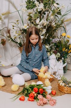 Two girls in a beautiful Easter photo zone with flowers, eggs, chickens and Easter bunnies. Happy Easter holiday