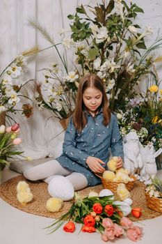 Two girls in a beautiful Easter photo zone with flowers, eggs, chickens and Easter bunnies. Happy Easter holiday