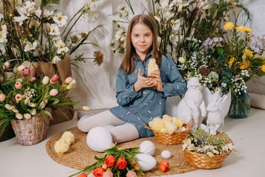 Two girls in a beautiful Easter photo zone with flowers, eggs, chickens and Easter bunnies. Happy Easter holiday