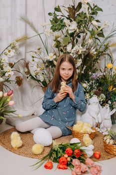 Two girls in a beautiful Easter photo zone with flowers, eggs, chickens and Easter bunnies. Happy Easter holiday