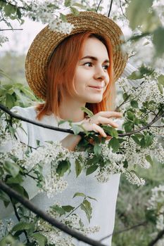 Portrait of a woman in a straw hat in a cherry blossom. Free outdoor recreation, spring blooming garden