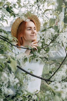 Portrait of a woman in a straw hat in a cherry blossom. Free outdoor recreation, spring blooming garden