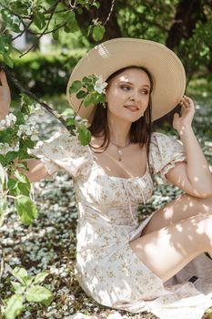 An attractive long-haired woman walks in the spring in the park of blooming apple trees. Spring portrait of a woman