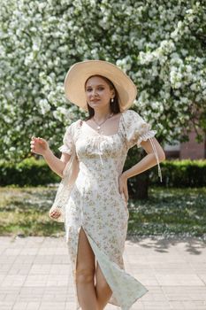 An attractive long-haired woman walks in the spring in the park of blooming apple trees. Spring portrait of a woman