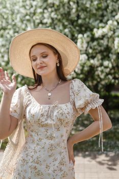 An attractive long-haired woman walks in the spring in the park of blooming apple trees. Spring portrait of a woman