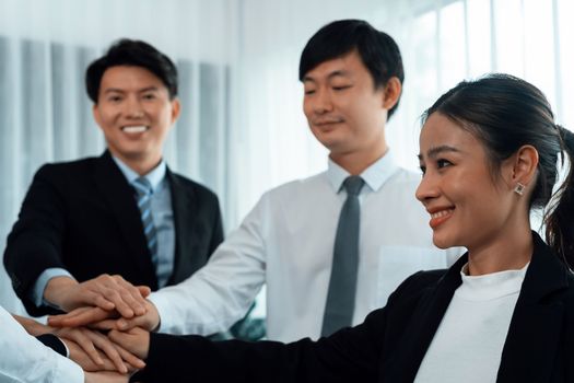 Closeup business team of suit-clad businessmen and women join hand stack together and form circle. Colleague collaborate and work together to promote harmony and teamwork concept in office workplace.