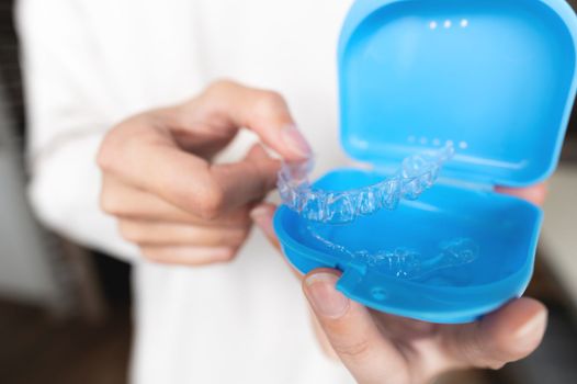 Close-up of a plastic transparent brace in a box in the hand of a young woman. selective focus.