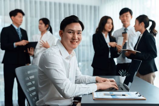 Portrait of focus young successful confident male manager, executive wearing business wear in harmony office arm crossed with blurred meeting background of colleagues, office worker.