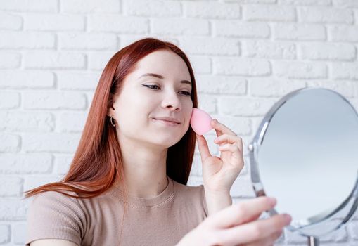 young beautiful woman holding make-up brushes and making up with cosmetics set at home. Natural beauty