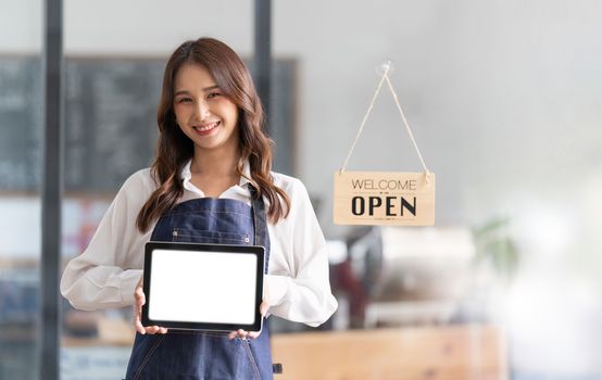 portrait of a woman wearing an apron holding a digital tablet with a blank white screen. Waiter holding a touch screen tab with copy space for your text