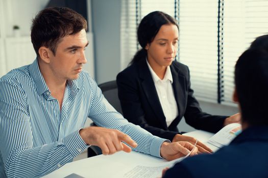 Competent office workers from various nationalities are debating, discussing and brainstorming in the meeting room. A group of employees is collaborating to achieve their business objectives.