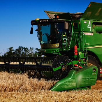 John Deere harvester works in the field. Combine Harvesting Wheat. Field field of cereals during harvesting. Modern equipment works. 07.07.22, Rostov region, Russia.